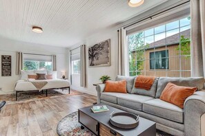 A modern living room with a sofa, a coffee table, and a bed. - Del Norte Cottage! Downtown Home w/ BBQ & Fire Pit (Colorado Springs)