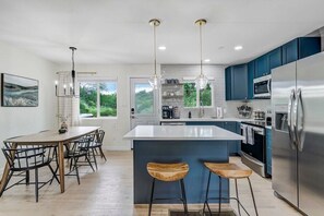 Enjoy cooking in this well-lit kitchen with a large island and bar stools, stainless steel appliances, and an oven.