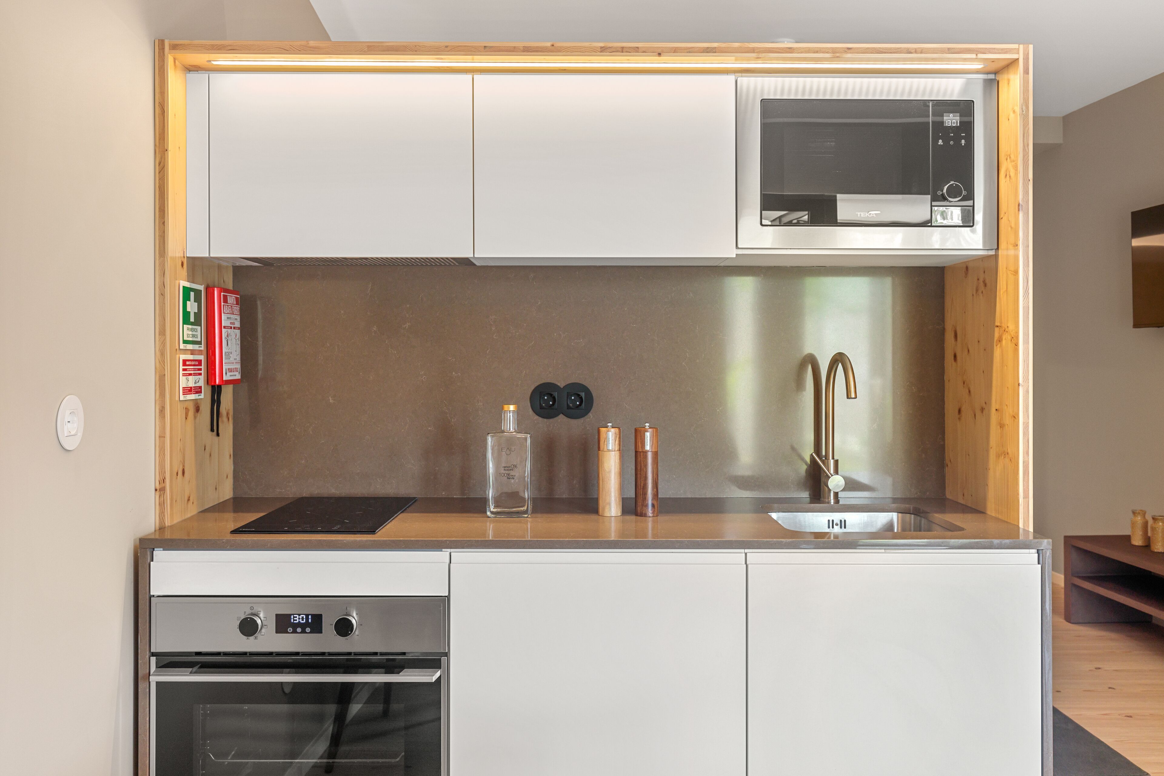 Une cuisine compacte équipée d’un four à micro-ondes, d’un four traditionnel et d’un évier.