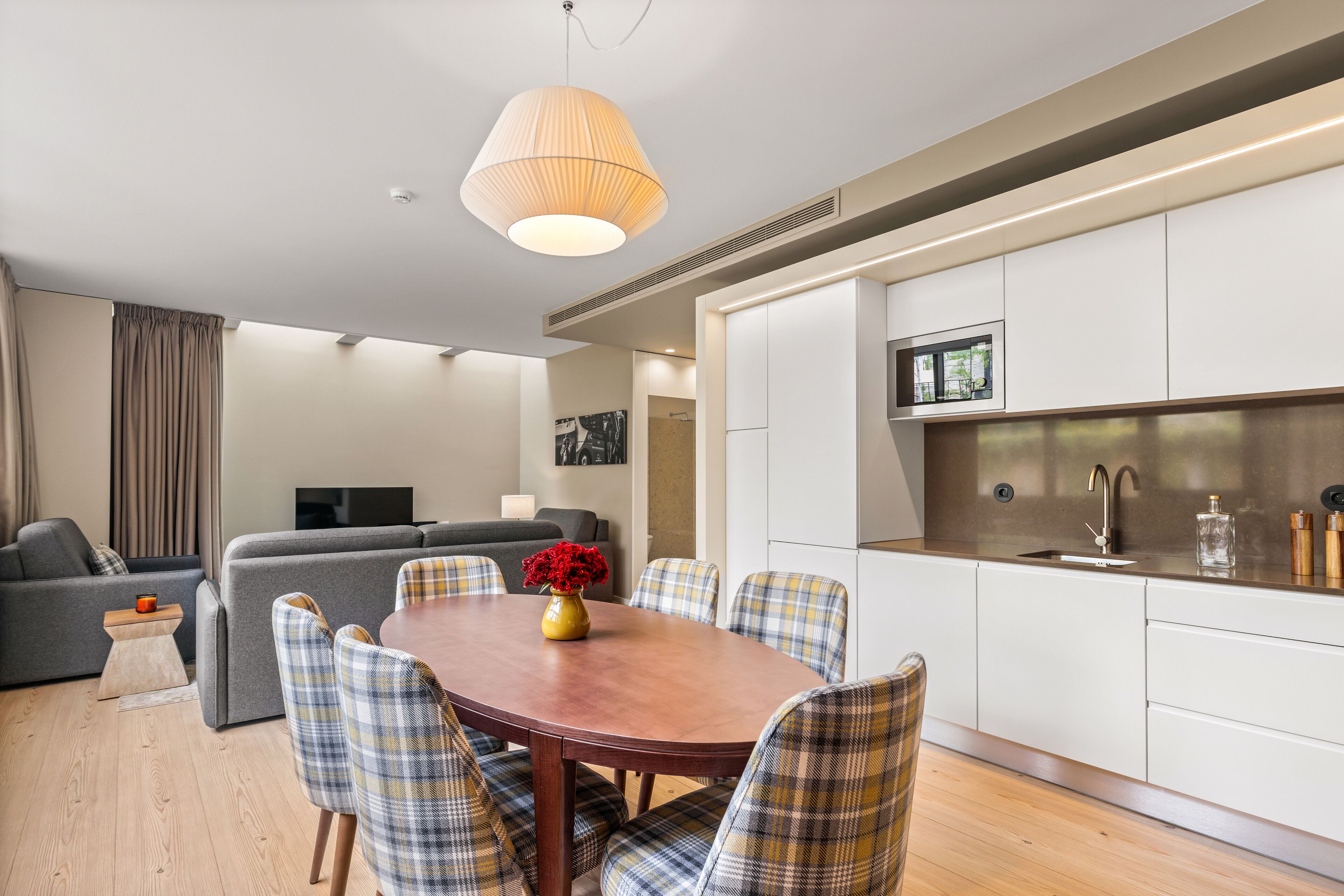 A modern living room with a dining table, sofa, and kitchen area.