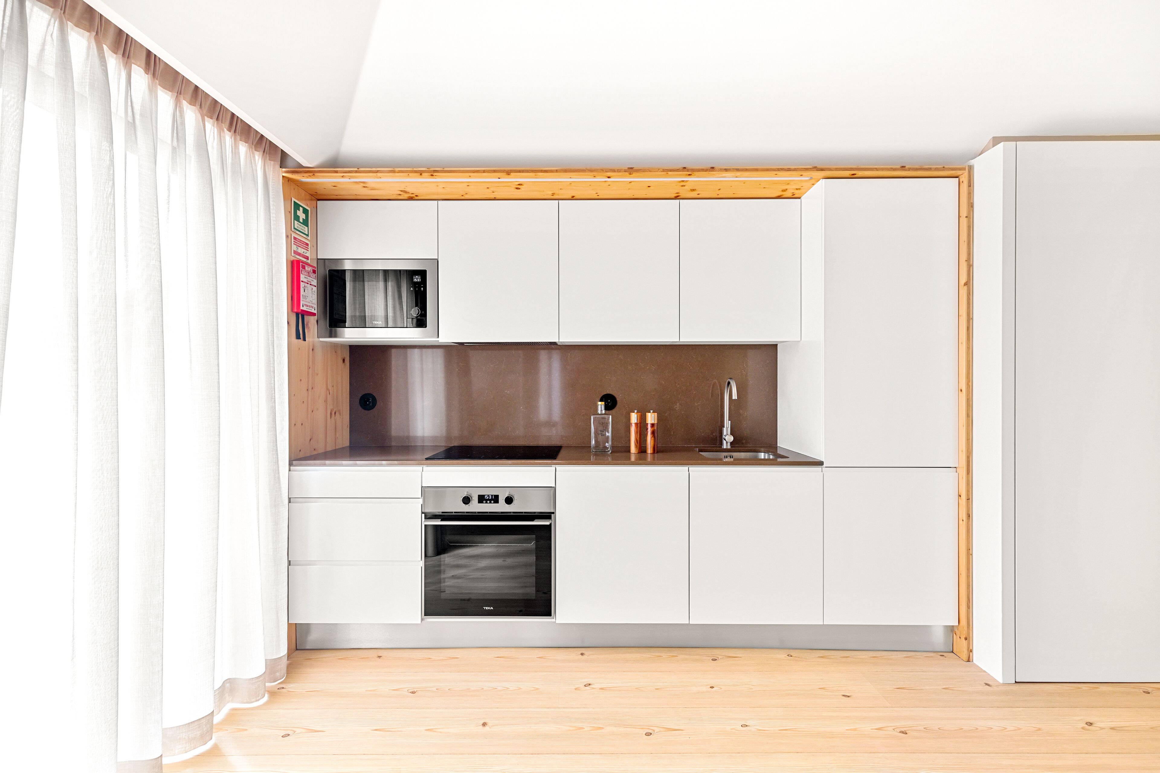 A compact kitchen with white cabinets, a microwave, a stove, and a sink.