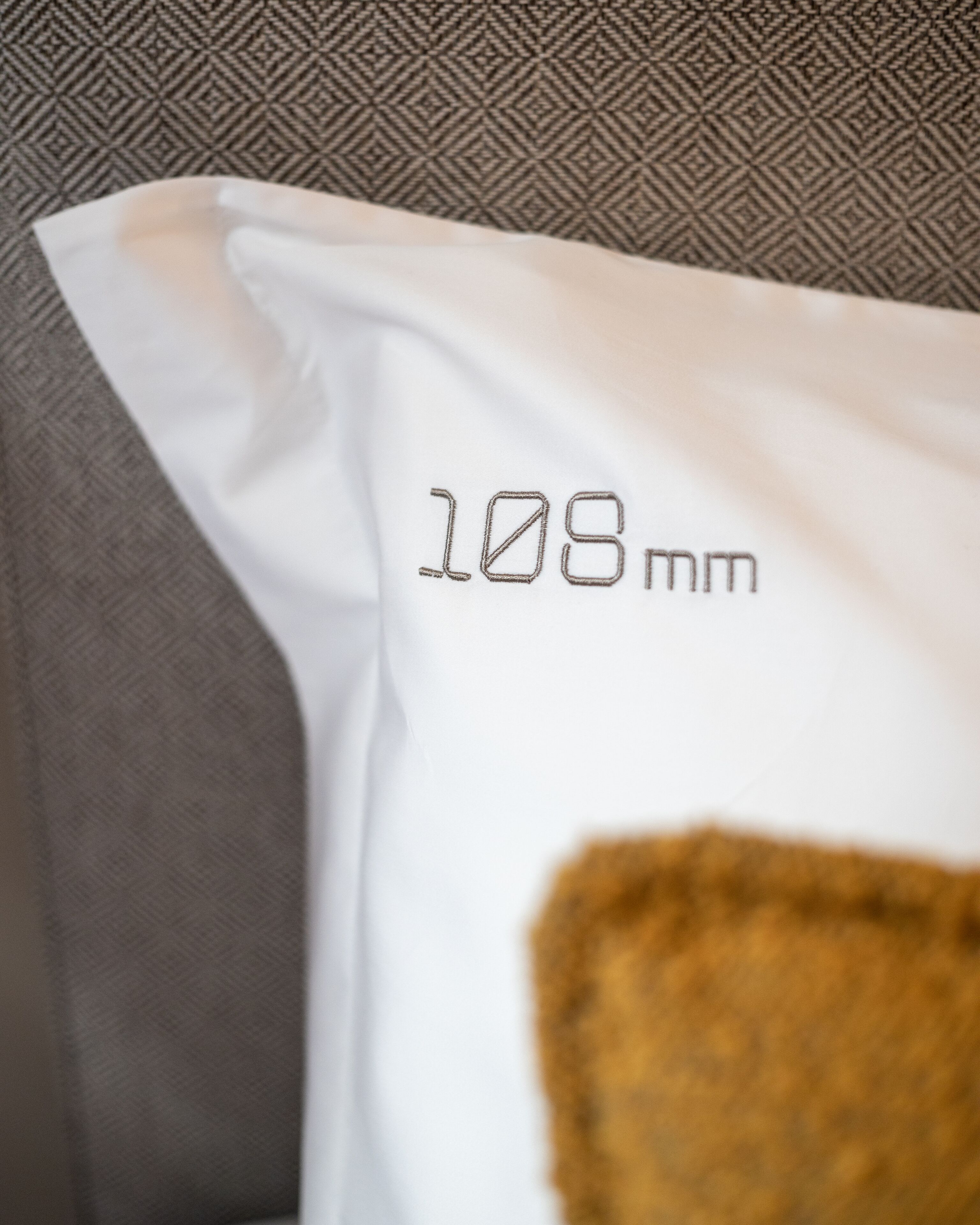 Almohada blanca con el número "108 mm" bordado.