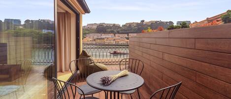 Ein Balkon mit rundem Tisch und vier Stühlen, Blick auf eine Stadtansicht und eine Holzwand.