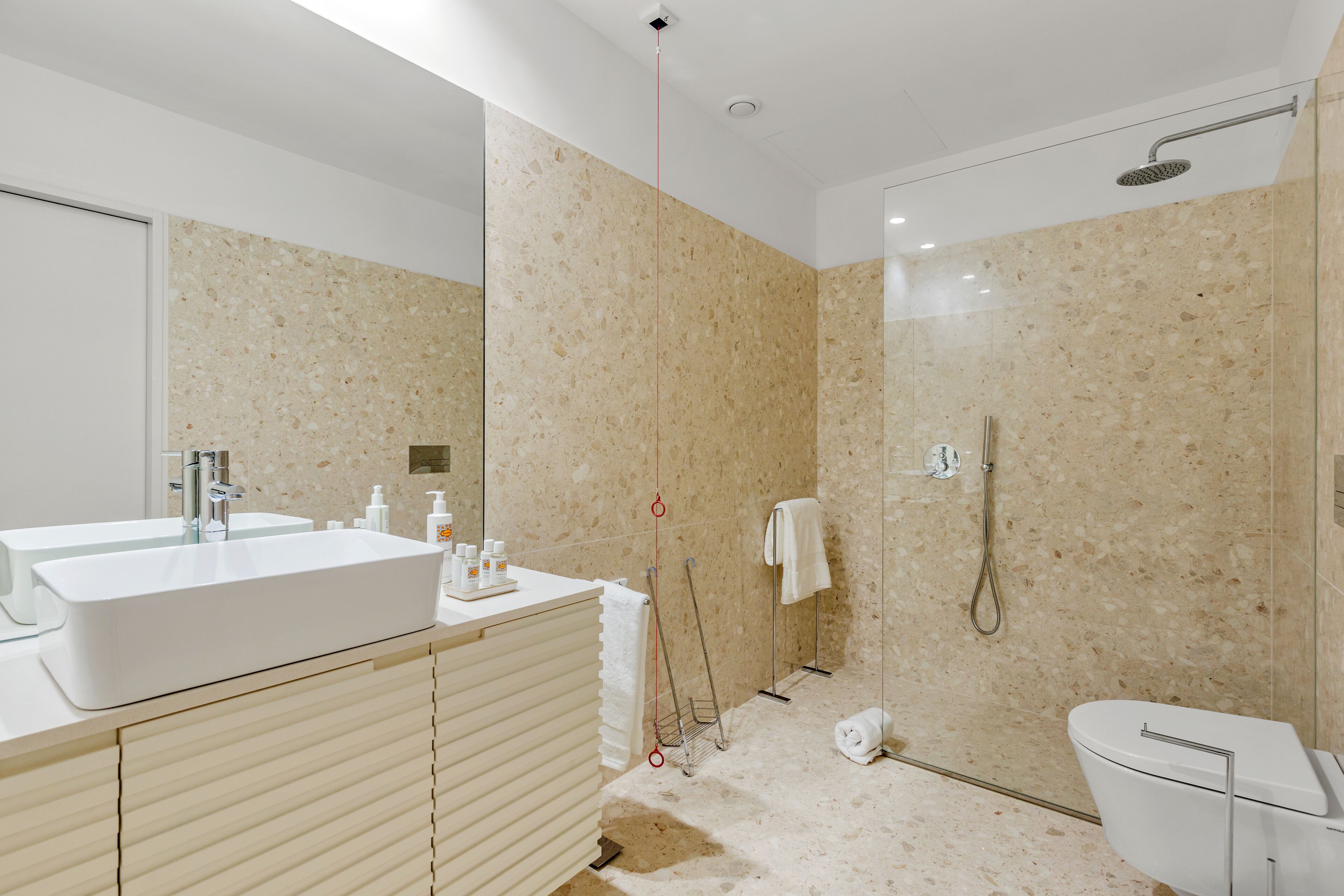 A modern bathroom with a large sink, mirror, and shower.