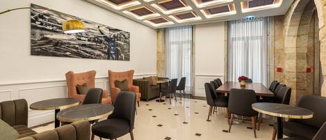 A modern dining area with a high ceiling, a large painting, and a stone wall.
