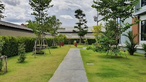 Un jardín bien cuidado con un sendero central, rodeado de setos ordenados y diversas especies de árboles.
