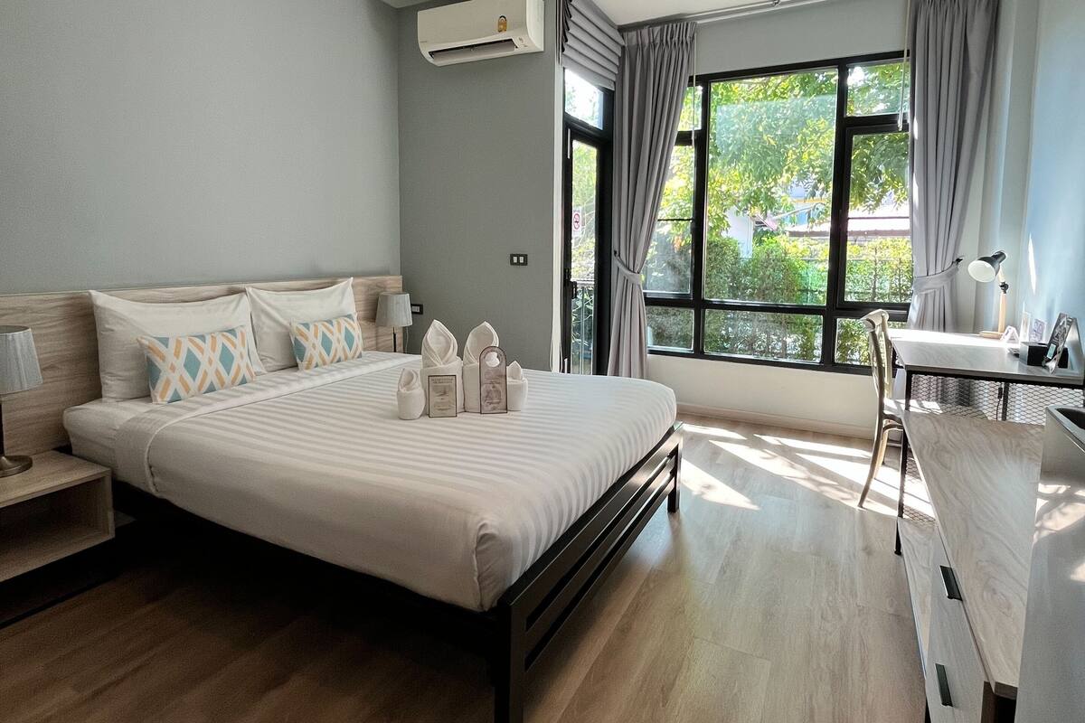 Ein modernes Hotelzimmer mit einem großen Bett, einem Schreibtisch und einem fenster mit Vorhängen.