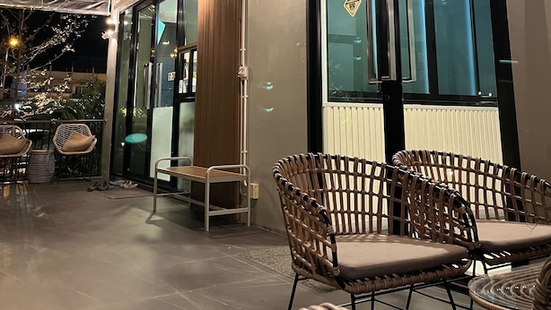 Un interior moderno con puerta de cristal, sillas de mimbre y techo con vigas a la vista.
