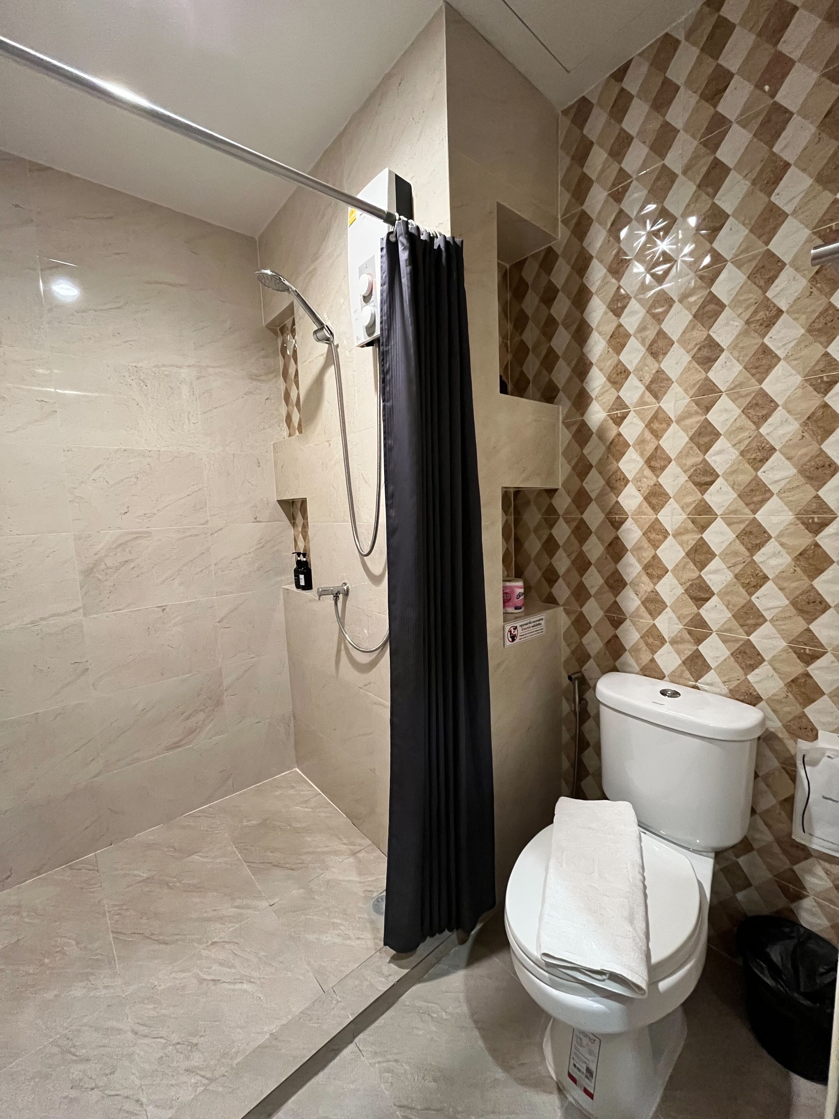 A modern bathroom with a shower, toilet, and a checkered wall pattern.