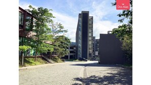 A modern building with a glass facade, surrounded by trees and a paved area. - Near everything! (Santa Tecla)