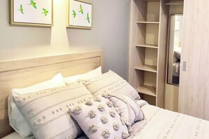 A bedroom with a wooden headboard, a bed with patterned pillows, and a closet with shelves.