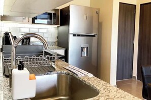 A modern kitchen with a stainless steel sink, dishwasher, and refrigerator.