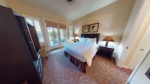 A bedroom with a bed, two bedside tables with lamps, a dresser, and a door leading to a balcony. - LV111 One Bedroom Legacy Villa Near Main Pool (La Quinta)