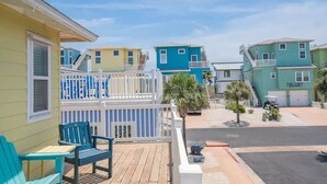 A row of colorful houses with a wooden deck and a white fence. - Village Walk 3 BR/2.5 Bath--Shared Heated Pool and Close to the Beach! (Port Aransas)