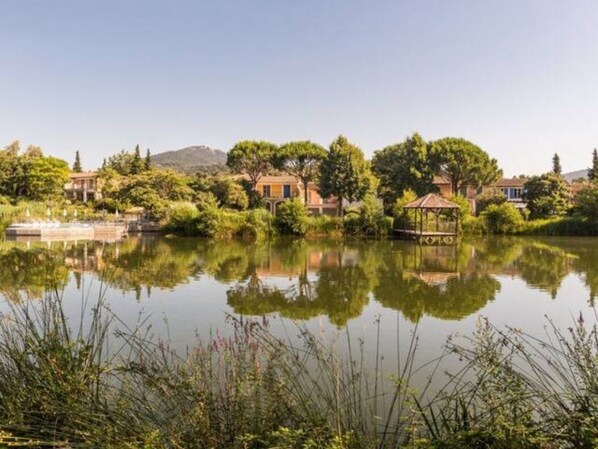 A serene lakeside property with a gazebo, reflecting the surrounding trees and buildings.
