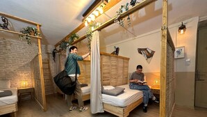 Una habitación acogedora con una cama de madera, una mesita de noche pequeña y una planta colgante.