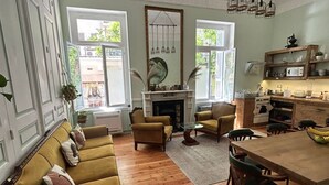 Un amplio salón con un conjunto de sofás, una chimenea y un comedor, con una cocina al fondo.