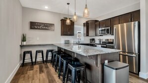 A modern kitchen with a central island, stainless steel appliances, and bar stools. - Next to Indoor and Outdoor Pools! Hot Tub! Great views! 2 Living Rooms (Branson)