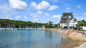 A beach with boats, a sandy shore, and a building with a blue roof. - Appart Hôtel & Spa La Villa Du Port (Vannes)