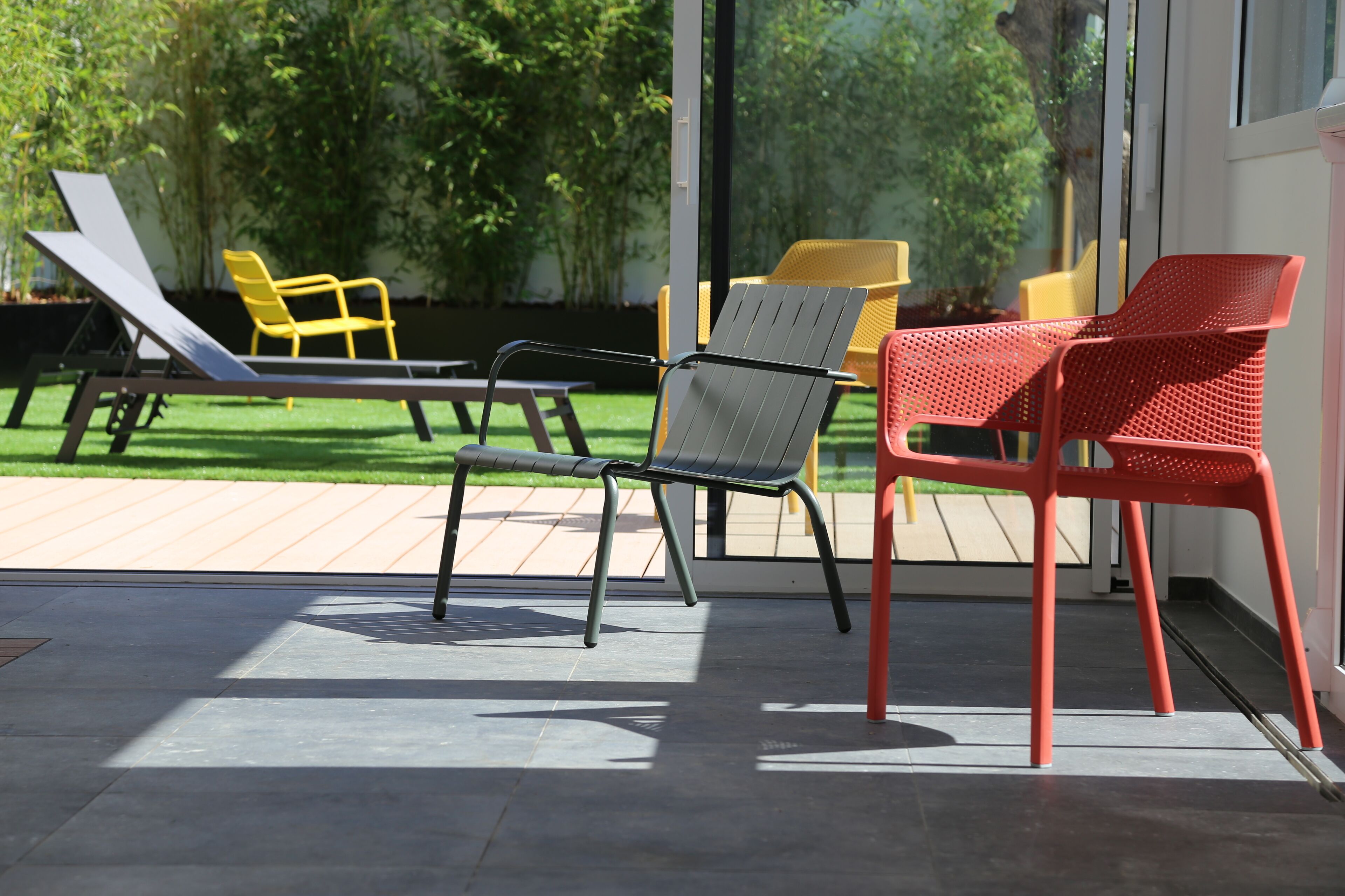An outdoor seating area with modern chairs and a glass door leading to a garden.