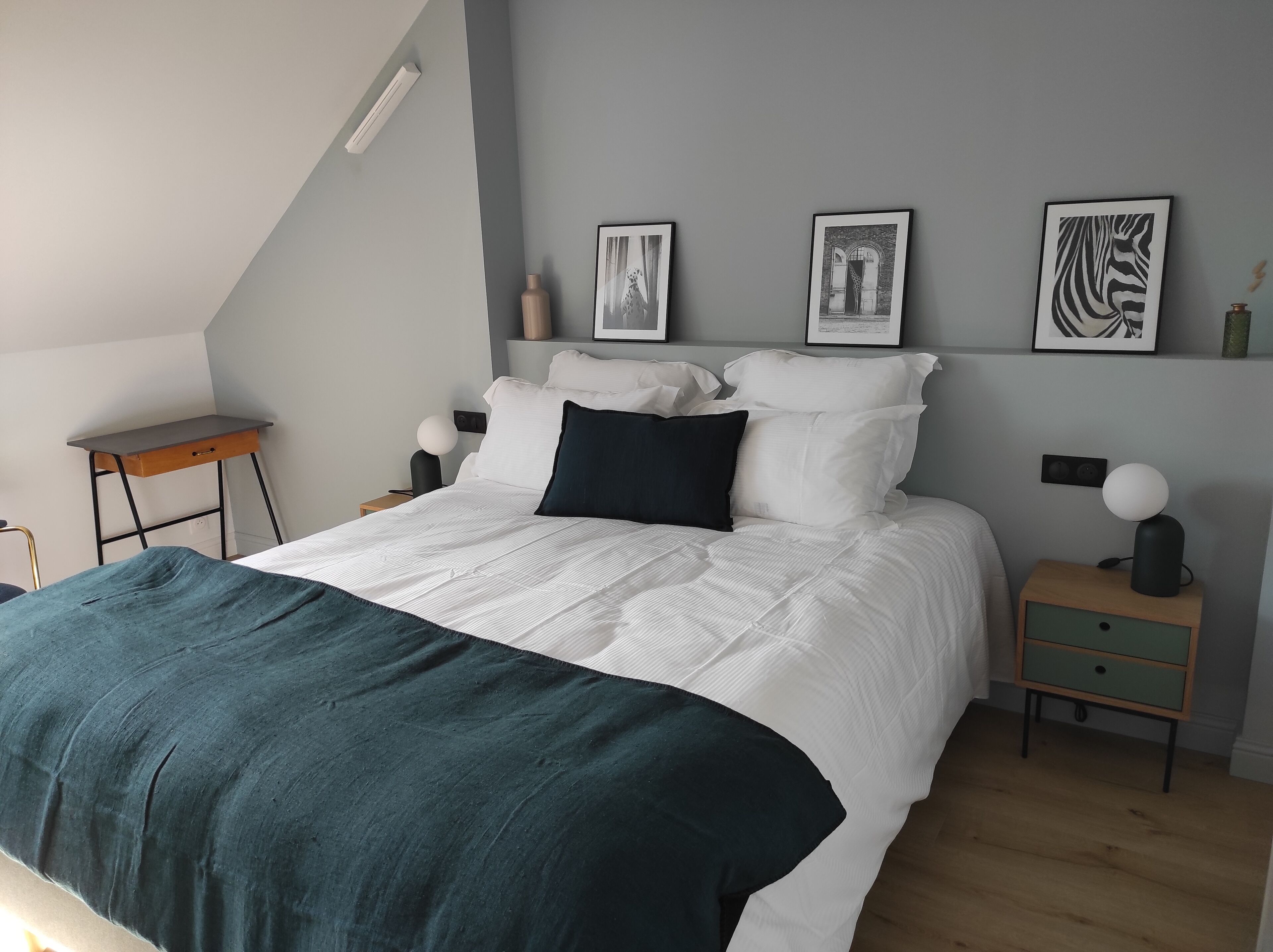 A modern bedroom with a bed, bedside tables, and wall-mounted artwork.