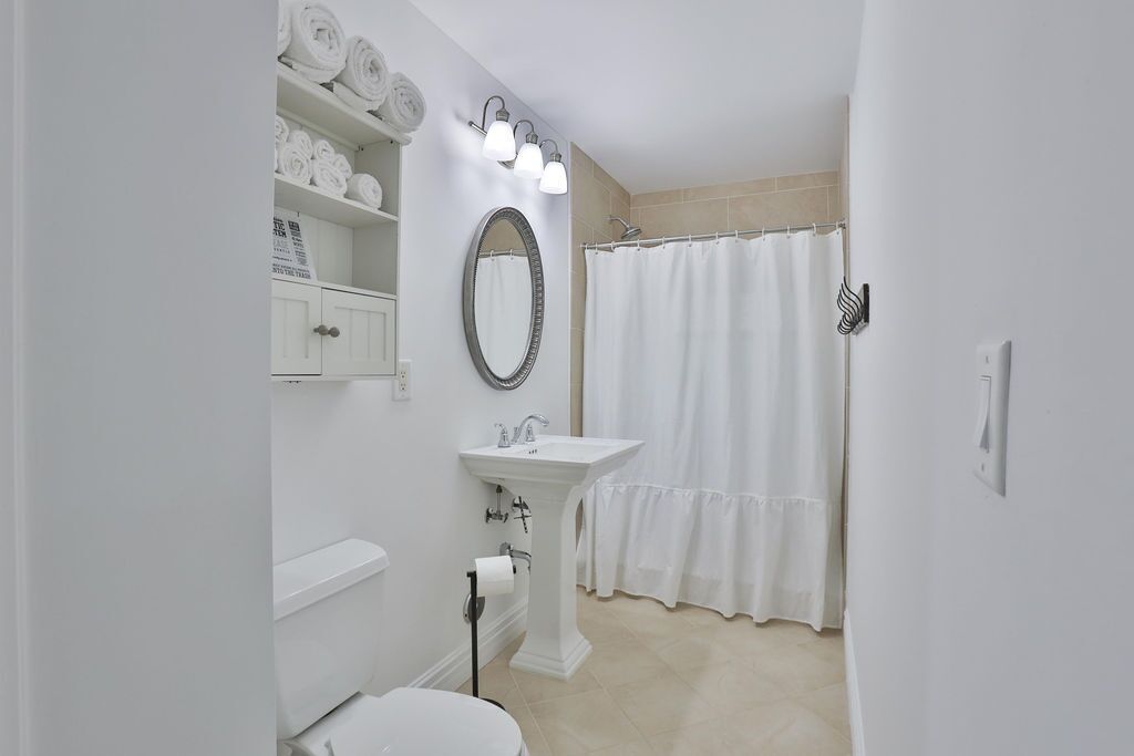 A bathroom with a white sink, a mirror, a toilet, and a shower curtain.