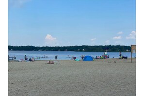Enjoy a serene beach experience surrounded by lush trees and calm waters.