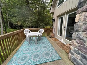 Relax on the deck with a view of lush greenery, surrounded by a stone wall and a wooden railing.