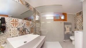 Et moderne badeværelse med en stor hvid vask, bruser og toilet.