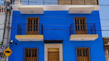 A two-story building with a blue facade, wooden doors, and balconies.