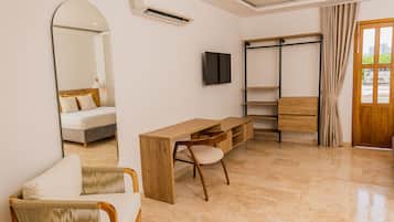 Una habitación de hotel moderna con una cama, un escritorio de madera, una silla, un televisor, un armario y un espejo grande.