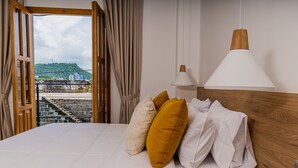 Een hotelkamer met een bed, uitzicht op een stadsbeeld en een houten hoofdbord.