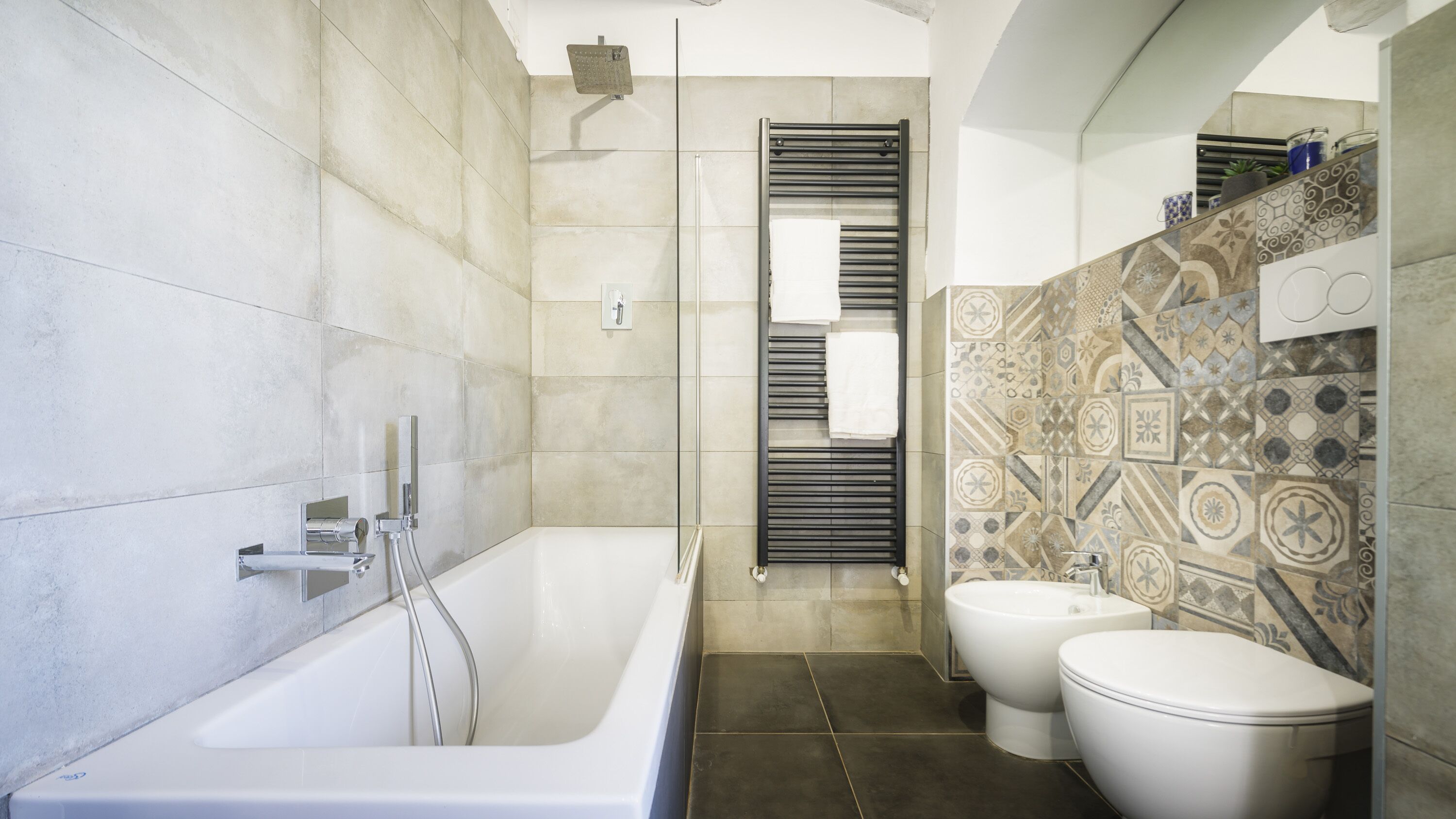 Een moderne badkamer met een bad, twee toiletten en een douche.