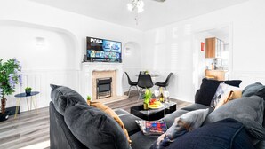 Una sala de estar moderna con chimenea, televisor de pantalla plana y ventilador de techo.