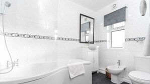 Un baño moderno con una bañera independiente, un lavamanos, un bidé y un inodoro.