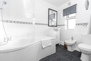 A modern bathroom with a freestanding bathtub, a sink, a bidet, and a toilet.
