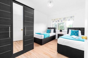 A bedroom with two beds, a wardrobe, and a window with a view.