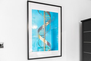 A framed artwork of a spiral staircase against a white wall.