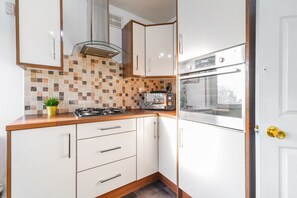 A kitchen with white cabinets, a tiled backsplash, a stove, and an oven.