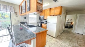 A kitchen with granite countertops, wooden cabinets, a refrigerator, a microwave, and a stove.