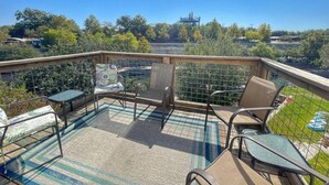 A balcony with a view of a bridge, surrounded by greenery and a tiled floor.