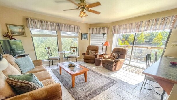 A spacious living room with a sofa, armchairs, a coffee table, and a dining area with a table and chairs.