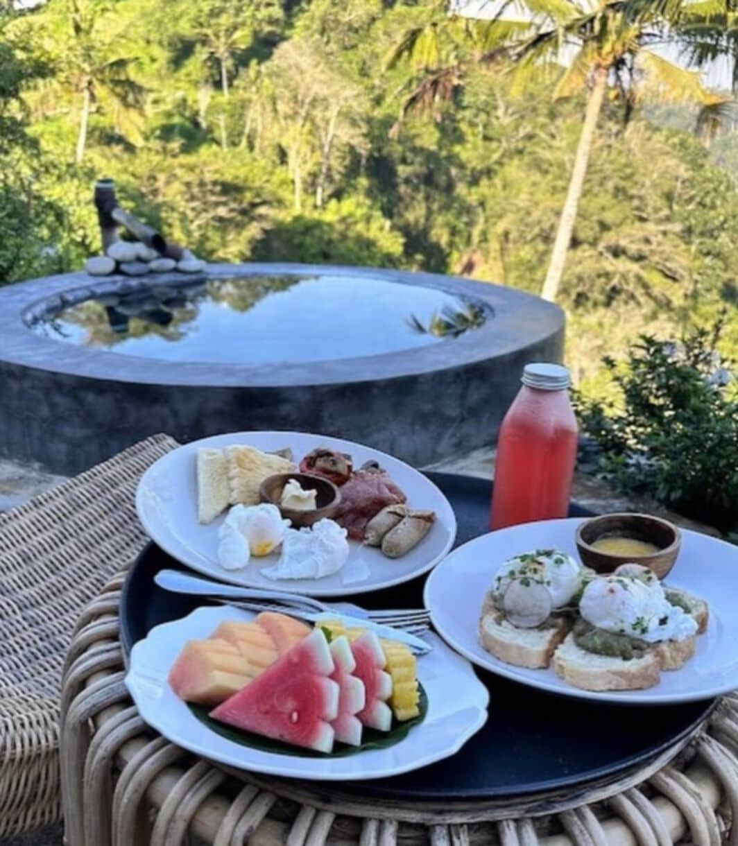 A dining table with plates of food, a water bottle, and a hot tub in the background.