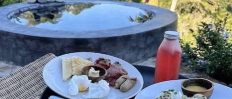 A dining table with plates of food, a water bottle, and a hot tub in the background.