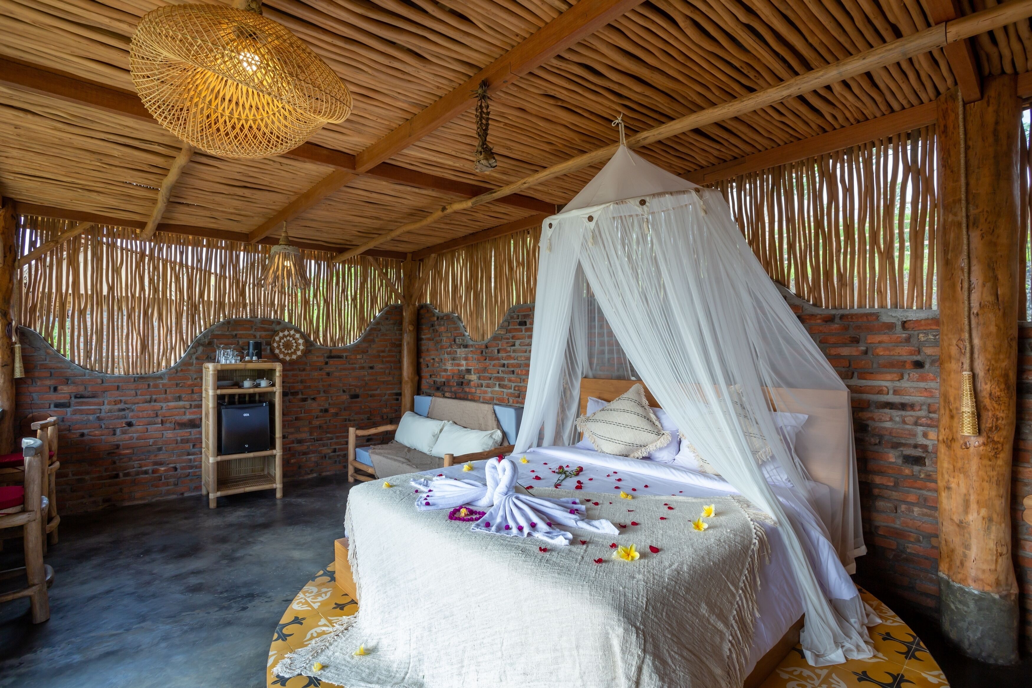Una habitación con una cama, una silla de madera, una mesita y una lámpara colgante.