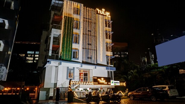 Een hotel met een moderne gevel, verlichte signage en een verticale tuin.