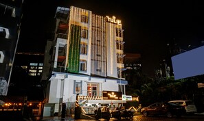 Un hôtel doté d’une façade moderne, d’une enseigne lumineuse et d’un jardin vertical.