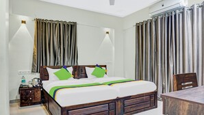 Een hotelkamer met een houten bed, twee nachtkastjes, een bureau en gordijnen.