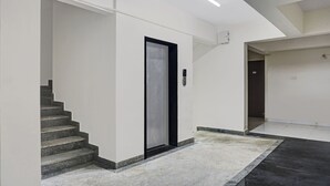 Een modern interieur met een trap die leidt naar een overloop, een deur met bedieningspaneel, en een strak, minimalistisch design.