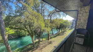 Un balcon donnant sur une rivière et des arbres.